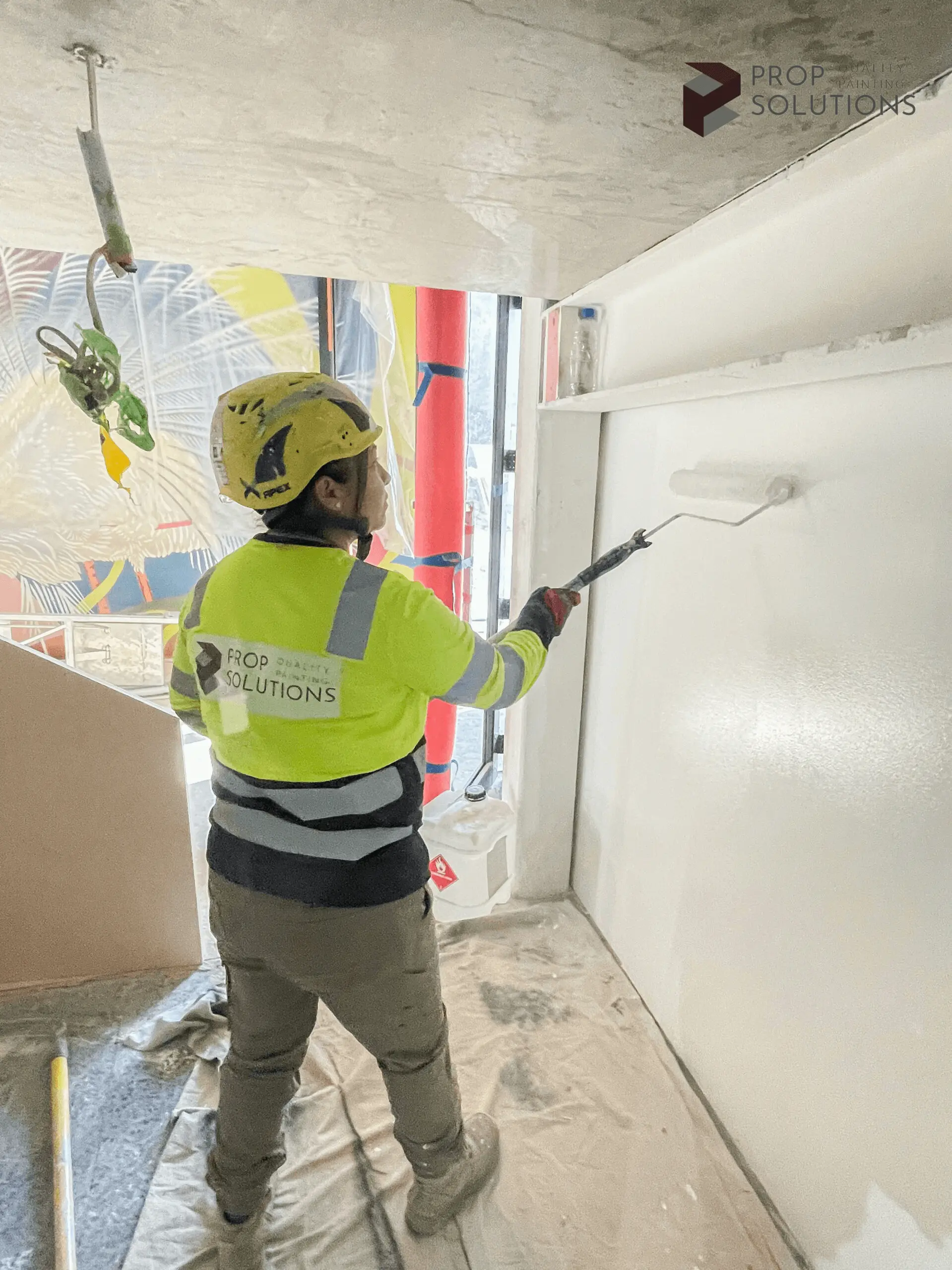 worker painting wall with a roller