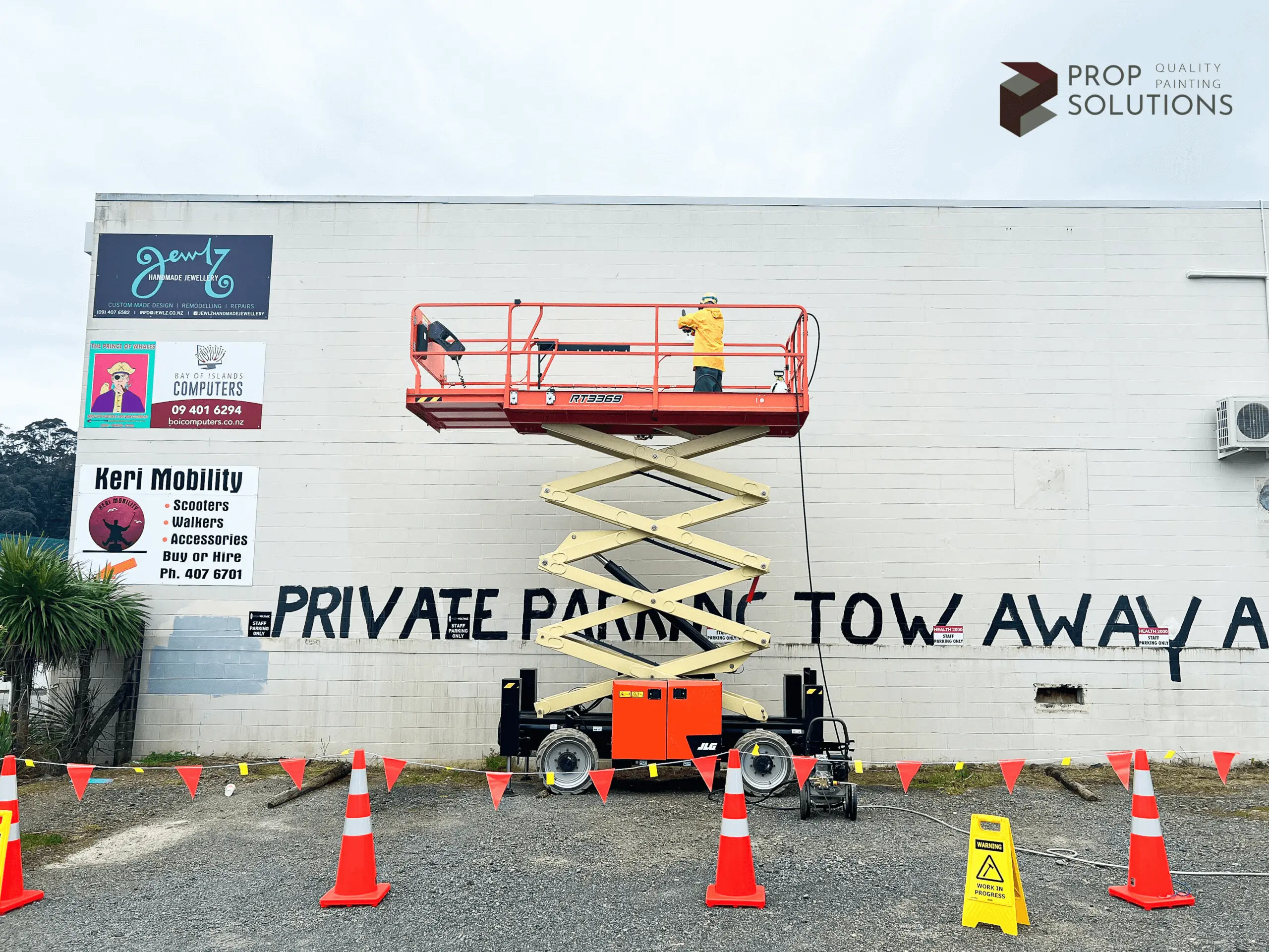 Picture of a worker on a scissor lift pressure washing a wall